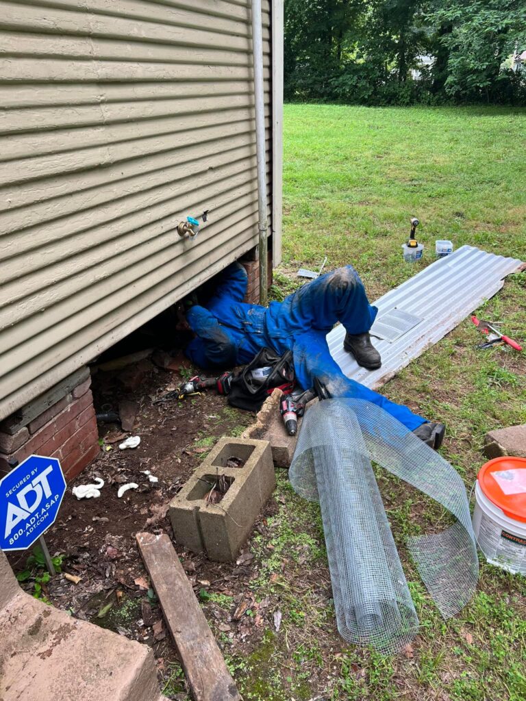 Pest control technician working in crawlspace for pest exclusion and repair